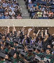 Nursing school graduates throw handfuls of confetti and glitter in celebration after Virginia Commonwealth University announces their degrees are conferred during Saturday’s ceremony at the Richmond Coliseum.