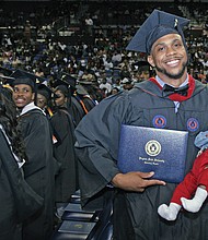 Shaquille Robinson, right, shows off his new bachelor’s degree and his young son, Shaquille Jr., during the afternoon commencement on Mother’s Day.