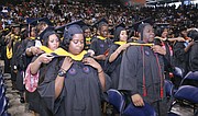 New graduates of Virginia State University help place each others’ hoods signifying their new degrees during commencement ceremonies Sunday at the VSU Multi-Purpose Center. Shaquille Robinson