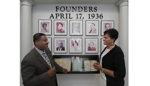 Randy N. Cooper, president and chief executive officer of Richmond Heritage Federal Credit Union, proudly shows off to his wife, Shirley G. Cooper, a wall display at the credit union's Commerce Road branch celebrating its founders. Mrs. Cooper is president and chief executive officer of the Credit Union of Richmond.