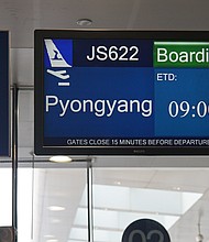 A departure screen shows "Pyongyang" as the journalists' destination, but they ended up flying to Wonsan.