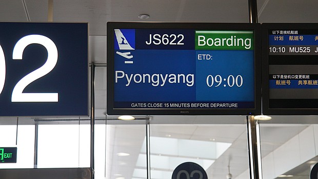 A departure screen shows "Pyongyang" as the journalists' destination, but they ended up flying to Wonsan.
