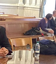 Michael Rotondo (left) at his eviction proceeding in Syracuse, New York. His parents, Mark and Christina, confer with their lawyer in the court gallery behind.  CREDIT: Douglas Dowty/The Syracuse Newspapers via AP