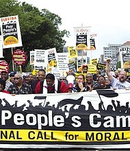 Demonstrators led by the Rev. William J. Barber II, center wearing red shirt, march outside the Capitol in Washington during last Saturday’s Poor People’s Campaign rally on the National Mall.
