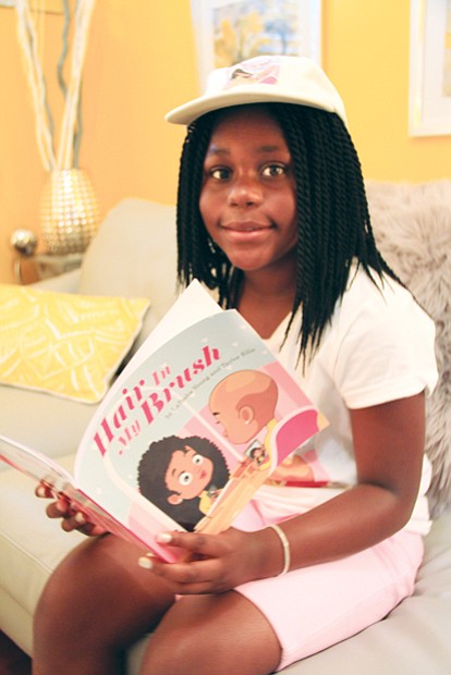 Taylor Ellis, 10, author of “Hair in My Brush” reviews a  copy of her book about a young African-American girl who is diagnosed with alopecia.