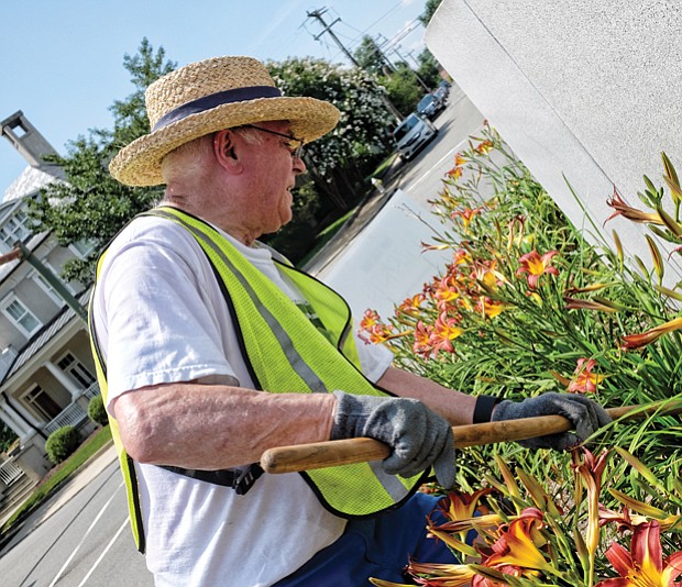 CITYSCAPE-Slices of life and scenes in Richmond-
Volunteers from the Richmond Tennis Association add touches of color, including their own green thumbs, to the Arthur Ashe Monument at Monument and Roseneath avenues in Richmond’s West End. Joe Grover cleans a bed of bright lilies. This is the fourth year that the association has conducted the beautification project.