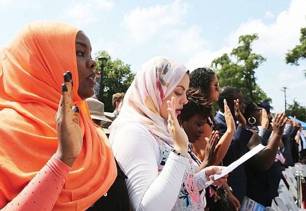 New citizens-
Judge Roger L. Gregory, chief judge of the 4th U.S. Circuit Court of Appeals in Richmond, talks to 96 immigrants and their family members during the Fourth of July naturalization ceremony where they officially became U.S. citizens. The ceremony was held outside the Virginia Museum of History and Culture on the Boulevard. Above left, Henrico County resident Hanan Mohamed, 26, a native of Sudan, takes the citizenship oath with people from more than 40 countries. 