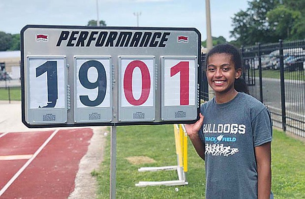 State long jump champion Natalie Barnes shows off the sign delineating the distance she jumped — 19-1 — to claim the title for the Stone Bridge Bulldogs.