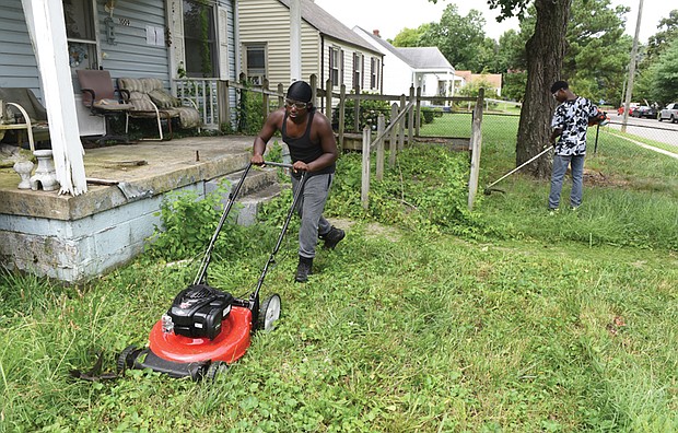 Michael Beckley, 17, mows the lawn while Xavier Edmonds, 16, whacks weeds last Saturday at a vacant home on Garber Street in Fulton before seeking customers for paying jobs through the 4-H Lawn Maintenance Program started by Wyatt Kingston. 
