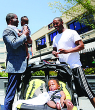 CELEBRATING A RICHMOND ICON-Richmond Mayor Levar M. Stoney holds 10-month-old Nasir Jackson while the infant’s dad, Timothy Jackson, and twin brother, Dakari, pause beside the statue of Richmond businesswoman Maggie L. Walker during Saturday’s celebration Downtown honoring her 154th birthday.