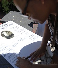 Sandra Jennings, 54, of Richmond signs a card for Maggie L. Walker during the celebration of Mrs. Walker’s 154th birthday Saturday at the plaza at Broad and Adams streets Downtown where Mrs. Walker’s statue has stood for the last year.