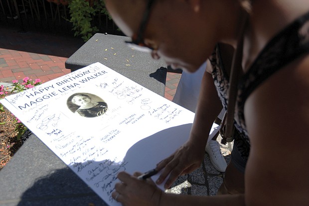 Sandra Jennings, 54, of Richmond signs a card for Maggie L. Walker during the celebration of Mrs. Walker’s 154th birthday Saturday at the plaza at Broad and Adams streets Downtown where Mrs. Walker’s statue has stood for the last year.