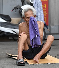 An elderly man wipes his face with a towel during a hot day in a residential district in Seoul.