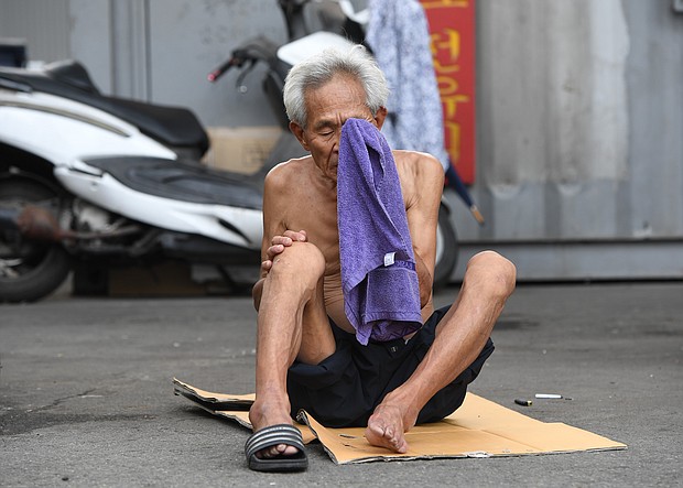 An elderly man wipes his face with a towel during a hot day in a residential district in Seoul.