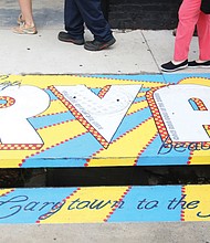 Mayor Levar M. Stoney takes part in a tour of the new artwork decorating four storm drains in Carytown. Here,  the tour stops at Melissa Rosener’s “A Postcard to the James” at Belmont and Cary streets. The goal: To encourage the public to help end pollution of city streams and the James River by not using storm drains as trash bins. 