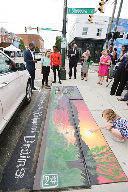 Mayor Levar M. Stoney takes part in a tour of the new artwork decorating four storm drains in Carytown. Here, the group is viewing Elise Neuschler’s “Deep Texas Beach” mural at Cary and Sheppard streets.
The goal: To encourage the public to help end pollution of city streams and the James River by not using storm drains as trash bins. 