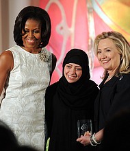 Former First Lady Michelle Obama (left) and then-Secretary of State Hillary Clinton pose with Samar Badawi of Saudi Arabia as she receives the International Women of Courage Award in 2012.