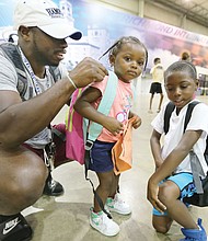 Justin-Mychal White, 28, adjusts the straps of his 2-year-old daughter Reagan’s new backpack last Saturday at the 10th Annual Back-to-School Rally sponsored by the Northside Coalition for Children. Reagan’s older brother, Jeremiah seems like an old pro with his new backpack. The 6-year-old will be a first-grader at Longdale Elementary School in Henrico County in the fall. The nonprofit coalition gave away the backpacks stuffed with school supplies at the Richmond Raceway.