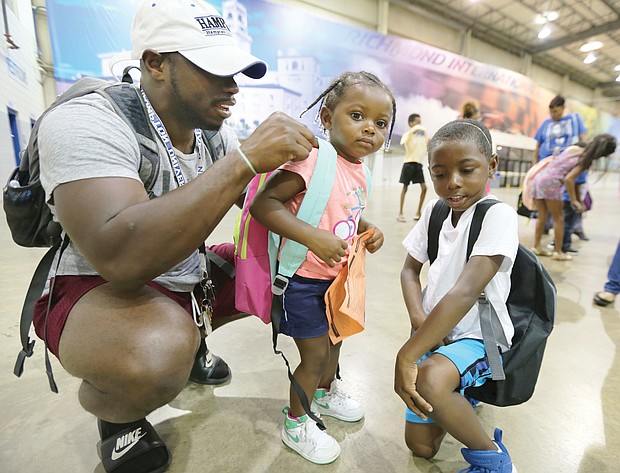 Justin-Mychal White, 28, adjusts the straps of his 2-year-old daughter Reagan’s new backpack last Saturday at the 10th Annual Back-to-School Rally sponsored by the Northside Coalition for Children. Reagan’s older brother, Jeremiah seems like an old pro with his new backpack. The 6-year-old will be a first-grader at Longdale Elementary School in Henrico County in the fall. The nonprofit coalition gave away the backpacks stuffed with school supplies at the Richmond Raceway.