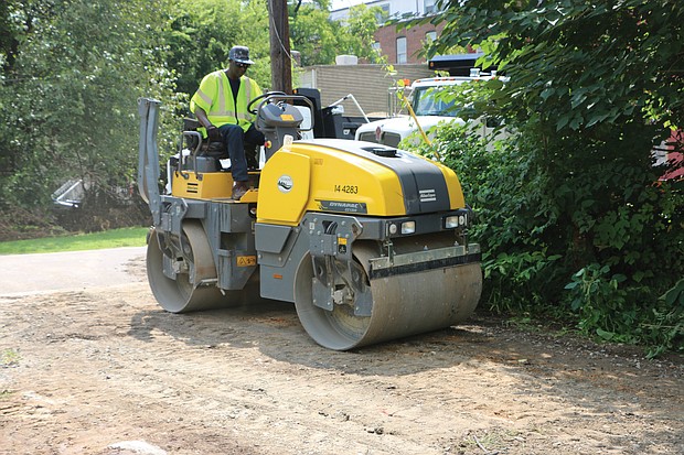 Jesse Hendren, above, uses a roller to pack down the dirt to improve an alley off Pink Street in Church Hill. He was part of a city Department of Public Works crew operating in the East End on Monday.