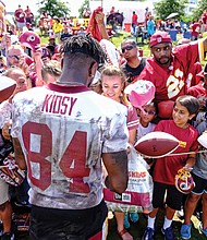 Hundreds of fans and autograph seekers flocked to the Washington professional football team’s training field to hobnob with their favorite players during last Saturday’s Fan Appreciation Day. Following practice, wide receiver Darvin Kidsy signs footballs and other team paraphernalia for fans of all ages.