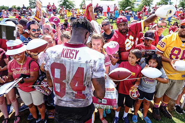 Hundreds of fans and autograph seekers flocked to the Washington professional football team’s training field to hobnob with their favorite players during last Saturday’s Fan Appreciation Day. Following practice, wide receiver Darvin Kidsy signs footballs and other team paraphernalia for fans of all ages.