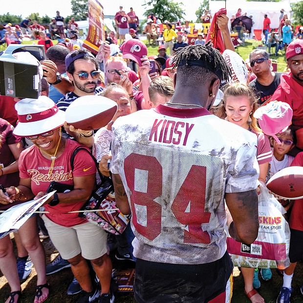 Hundreds of fans and autograph seekers flocked to the Washington professional football team’s training field to hobnob with their favorite players during last Saturday’s Fan Appreciation Day. Following practice, wide receiver Darvin Kidsy signs footballs and other team paraphernalia for fans of all ages.