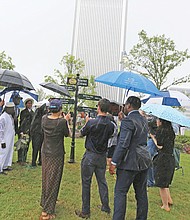 City officials and representatives of five overseas cities join Monday in unveiling Richmond’s new International Guidepost at Kanawha Plaza amid a downpour. The new sign celebrates Richmond’s Sister City relationship with Richmond upon Thames, England; Saitama City, Japan; Ségou, Republic of Mali; Windhoek, Namibia; and Zhengzhou, China. Saitama’s representatives included members of the Japanese city’s Little League baseball team. Richmond began a relationship with its English namesake in 1930 and began forging bonds with additional cities in 1980 after forming the 13-member Sister Cities Commission.