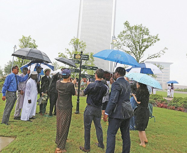 City officials and representatives of five overseas cities join Monday in unveiling Richmond’s new International Guidepost at Kanawha Plaza amid a downpour. The new sign celebrates Richmond’s Sister City relationship with Richmond upon Thames, England; Saitama City, Japan; Ségou, Republic of Mali; Windhoek, Namibia; and Zhengzhou, China. Saitama’s representatives included members of the Japanese city’s Little League baseball team. Richmond began a relationship with its English namesake in 1930 and began forging bonds with additional cities in 1980 after forming the 13-member Sister Cities Commission.