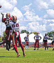 Hundreds of fans and autograph seekers flocked to the Washington professional football team’s training field to hobnob with their favorite players during last Saturday’s Fan Appreciation Day. Safety Kenny Ladler, left, cuts in to snatch a catch from wide receiver Cam Sims.