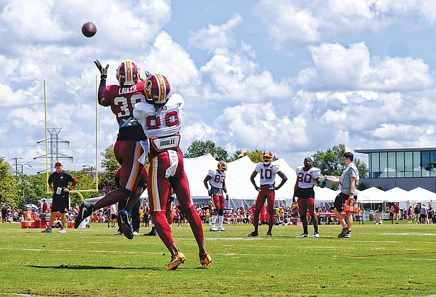 Hundreds of fans and autograph seekers flocked to the Washington professional football team’s training field to hobnob with their favorite players during last Saturday’s Fan Appreciation Day. Safety Kenny Ladler, left, cuts in to snatch a catch from wide receiver Cam Sims.