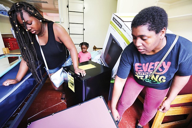 Left, Kavin Baines, 18, of Portsmouth gets a helping hand from her mother, Miki Baines, during last Saturday’s freshmen move-in at Virginia Union University. Orientation for members of the Class of 2022, along with classes for new students, started Monday on the Lombardy Street campus. Future student Kenzie Creekmur watches and takes notes about dormitory life in the background. 