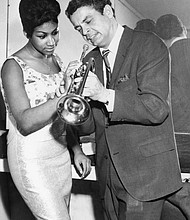 Aretha Franklin is taught how to properly play a trumpet by Canadian trumpeter Maynard Ferguson at Chicago's Sutherland Hotel in 1964.