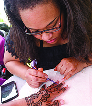 Happily Natural Day
Nikesha Wilson of Agape Henna decorates the hand of Felicia Mason during the festival.  The 16th annual event, held at the 5th District Mini Farm on Bainbridge Street in South Side, highlighted healthy eating and living and food self-sufficiency through gardening and cooking workshops, garden tours, music, food and other vendors. Left,