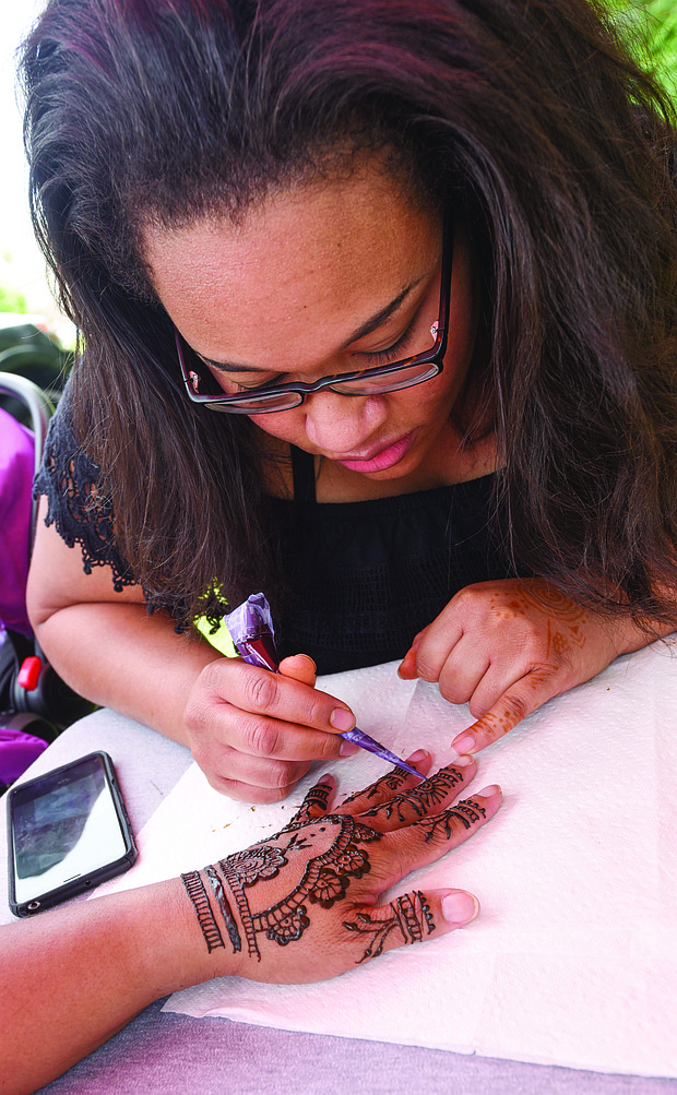 Happily Natural Day
Nikesha Wilson of Agape Henna decorates the hand of Felicia Mason during the festival.  The 16th annual event, held at the 5th District Mini Farm on Bainbridge Street in South Side, highlighted healthy eating and living and food self-sufficiency through gardening and cooking workshops, garden tours, music, food and other vendors. Left,