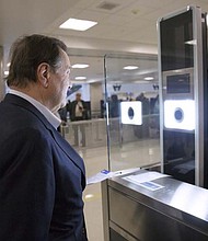 As part of CBP’s one-to-one biometric facial recognition testing on inbound, international flights, a traveler has his photo taken and compared against his passport photo to confirm his identity at Dulles Airport. Photo by Glenn Fawcett