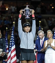 Naomi Osaka, 20, of Japan holds the single’s title trophy after defeating Serena Williams last Saturday in a game that will long be remembered.