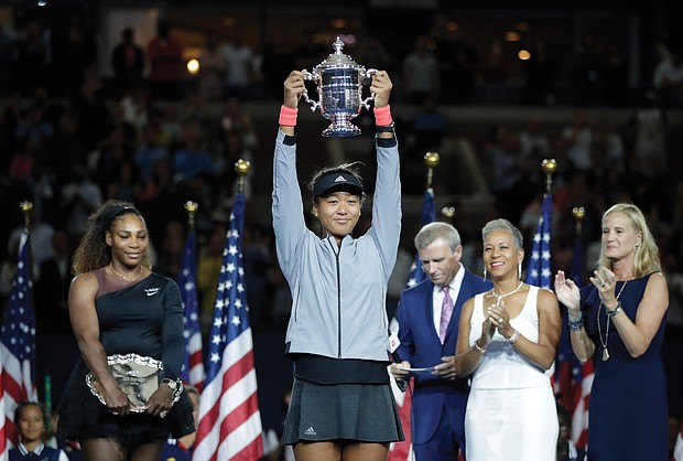 Naomi Osaka, 20, of Japan holds the single’s title trophy after defeating Serena Williams last Saturday in a game that will long be remembered.