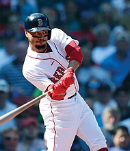 Mookie Betts of the Boston Red Sox hits a sacrifice fly to bring in a run during last Sunday’s game against the New York Mets in Boston.