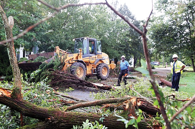 Crew members from the city Department of Public Works use chainsaws and heavy machinery to clean up downed trees and storm debris Tuesday along Lamont Street near Laburnum Avenue in North Side. 