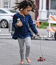 Walking the dog: Pets come in all types and sizes, including follow-behind toys. Zoe White, 4, looks to make sure her toy dog is following her at the STAY RVA Fest last Saturday on Bainbridge Street in South Side. The youngster is a pre-kindergarten student at Maymont Elementary School. (Sandra Sellars/Richmond Free Press)
