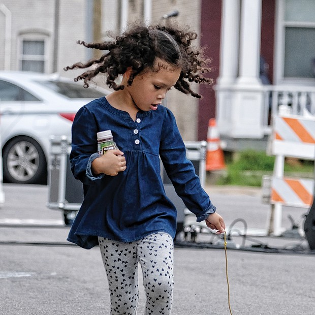 Walking the dog: Pets come in all types and sizes, including follow-behind toys. Zoe White, 4, looks to make sure her toy dog is following her at the STAY RVA Fest last Saturday on Bainbridge Street in South Side. The youngster is a pre-kindergarten student at Maymont Elementary School. (Sandra Sellars/Richmond Free Press)