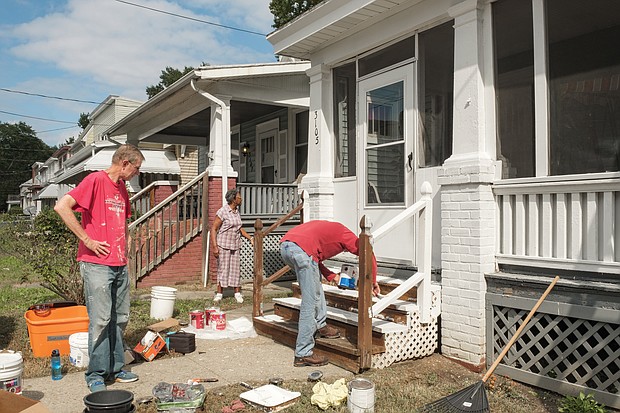 Volunteers Jeff Boisseau, left, and Chris Barrett put a fresh coat of paint on the Letcher Avenue home of Bernice Clack, center, during last Sunday’s “Day of Service,” sponsored by an alliance of churches and other organizations to assist Highland Park residents. 