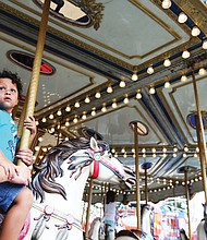 Fun at the fair: Gabby Wood takes a whirl on a merry-go-round with her 4-year-old son, Levi, last Sunday at the State Fair of Virginia. The annual event, featuring exhibits, farm animals, midway rides and food, runs through Sunday, Oct. 7, at the Meadow Event Park in Caroline County. (Regina H. Boone/Richmond Free Press)