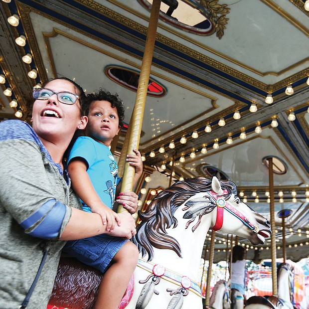 Fun at the fair: Gabby Wood takes a whirl on a merry-go-round with her 4-year-old son, Levi, last Sunday at the State Fair of Virginia. The annual event, featuring exhibits, farm animals, midway rides and food, runs through Sunday, Oct. 7, at the Meadow Event Park in Caroline County. (Regina H. Boone/Richmond Free Press)