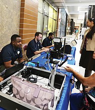 Tonya Ross, left, of the state Department of Motor Vehicles helps Jeraldine Williams take care of business on the first floor of City Hall last Friday as City Treasurer Nichole R. Armstead looks on. Ms. Ross is a member of the traveling team that operates the agency’s DMV Connect mobile unit that brings services to people rather than requiring them to go to a DMV customer service center. The mobile unit is scheduled to return to City Hall at 9th and Broad streets in Downtown from 9 a.m. to 4 p.m. the first Friday of each month. Other DMV Connect staff are, from left, Brandon Gunnell, Thomas Luck and Irvin Mitchell. 