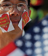 Wearing stickers on his face, an advocate attends “Rally for the American Dream – Equal Education Rights for All” in Boston ahead of the start of Monday’s court hearing in the lawsuit accusing Harvard University of discriminating against Asian-American student applicants.