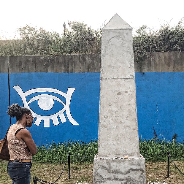 Anita Johnson reads the plaque at an obelisk erected in memory of the African-Americans buried on the site near Broad and 15th Street. (Sandra Sellars/Richmond Free Press)