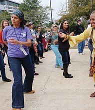 Janine Bell and Jarene Fleming stop and dance to the salsa sounds of Orquesta el Macabeo of Puerto Rico on Sunday at the Richmond Folk Fest. (Sandra Sellars/Richmond Free Press)