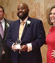 Rodney A. Robinson, the 2019 Virginia Teacher of the Year, holds the trophy he received Tuesday night at the awards ceremony at the Virginia Museum of Fine Arts. Congratulating him are Dr. James F. Lane, the state superintendent of public instruction, and Virginia First Lady Pam Northam.